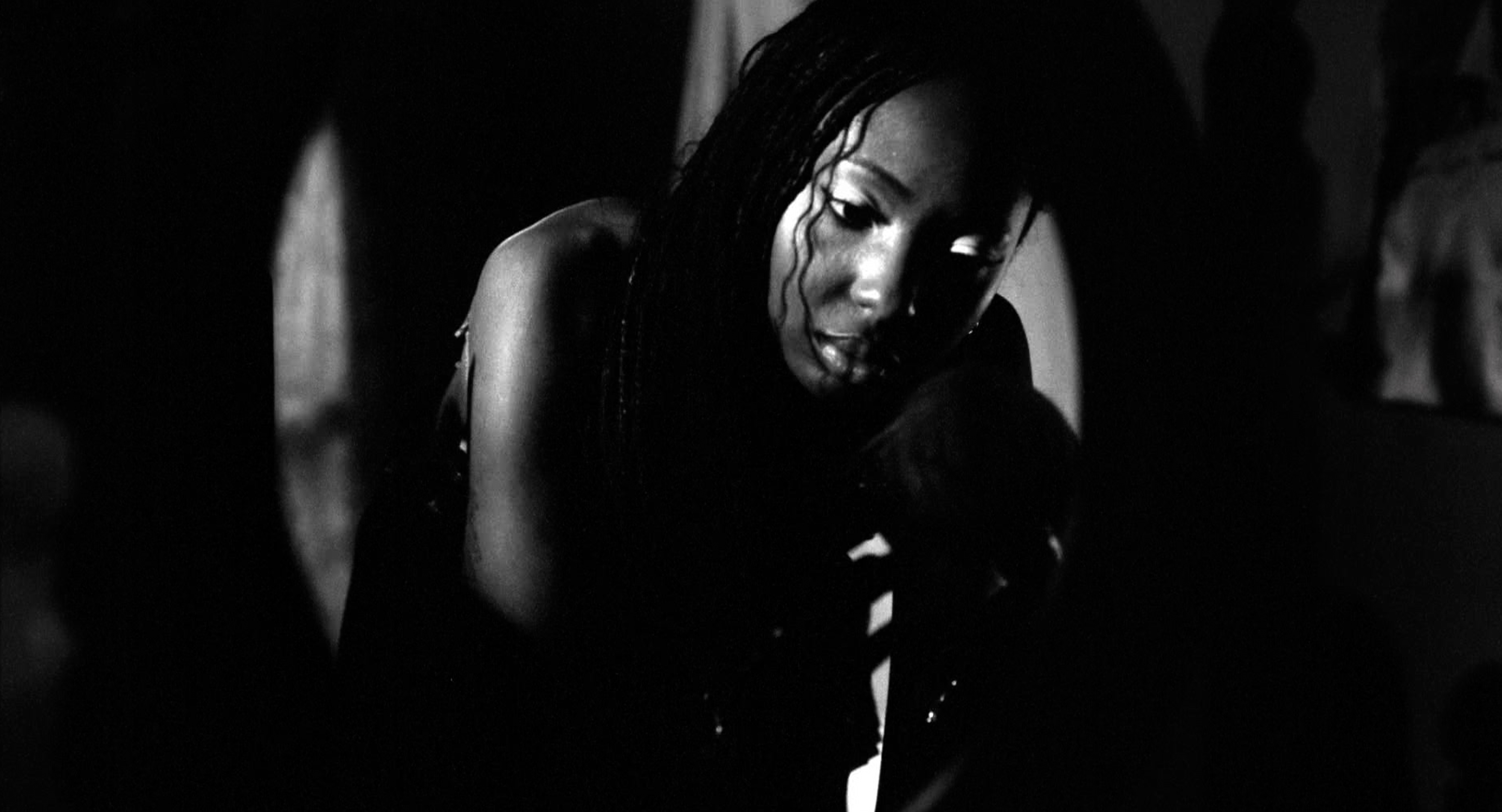 Black and white shot of a model with deep skin leaning towards the camera